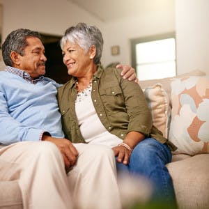 An older couple sits on the couch in their nice home.