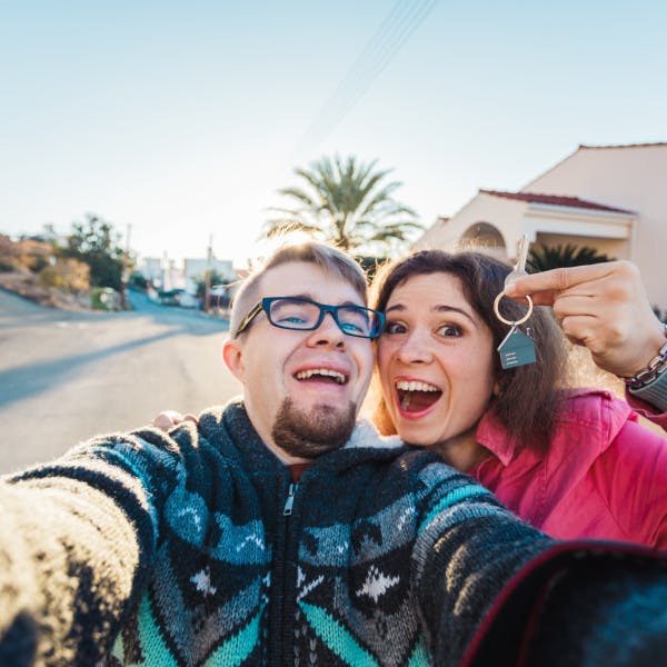 An excited young couple takes a selfie with the keys to their new home.