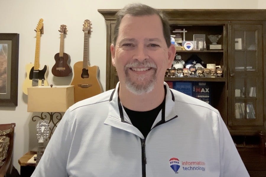 RE/MAX CIO Grady Ligon stands in his home office with his guitar collection in the background.