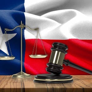 The Texas state flag behind a gavel and scales of justice.