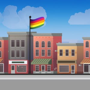 A Pride flag waves among a row of businesses on a typical main street. 