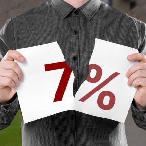 A man tears a sheet of paper with "7%" in half.