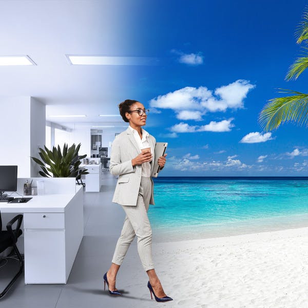 A woman in a business suit walks along a sandy beach next to a modern office.