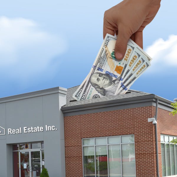 Building with Real Estate Inc. sign and hand with cash going into a slit on roof