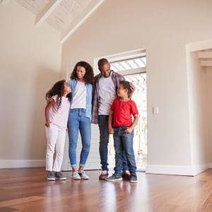 A Black family with children stands in their newly purchased home.