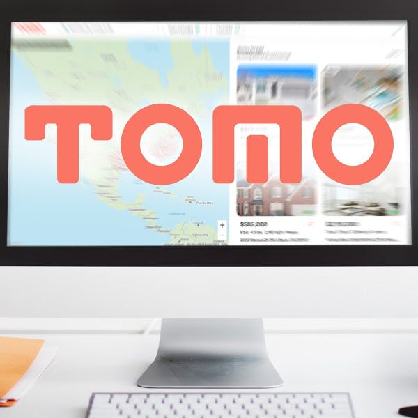 Tomo Real Estate search page on a desktop monitor