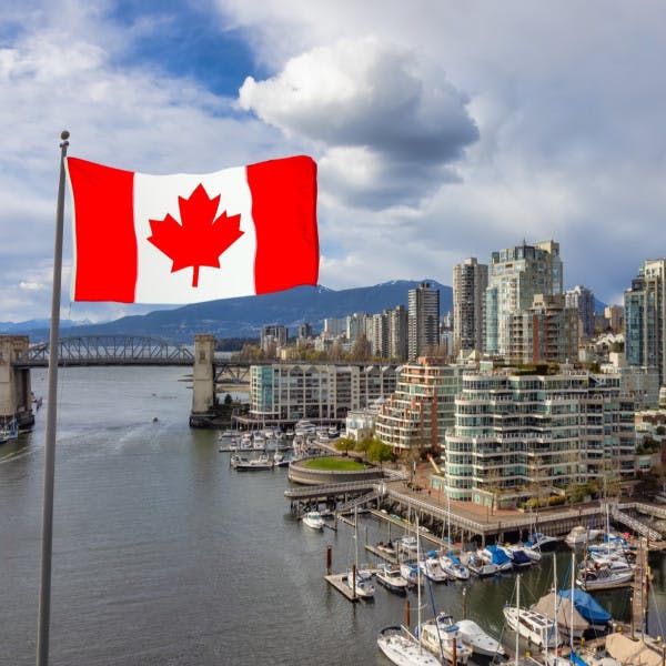 Canadian flag flying next to the city of Vancouver, BC. 