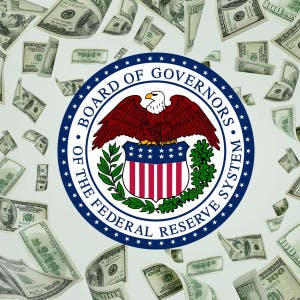 The Federal Reserve badge against a backdrop of hundred-dollar bills.
