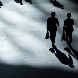 Silhouettes of white-collar workers walking with briefcases.