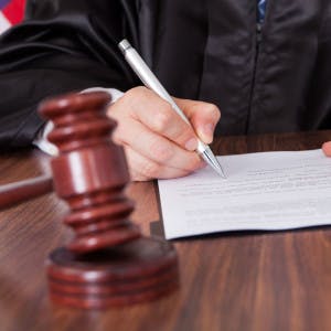 A judge sits at a desk signing legal papers