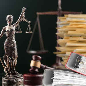 The scales of justice and a stack of legal papers and notebooks