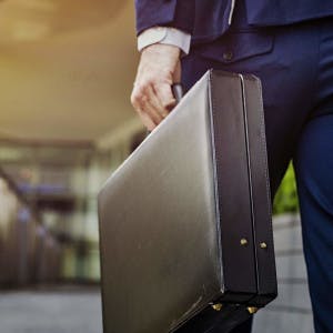 A business walks down a corridor with a briefcase.