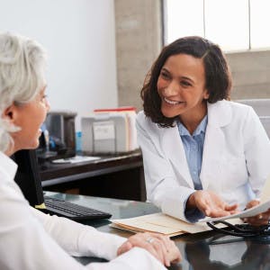 A doctor in an office discusses a medical chart with a patient.