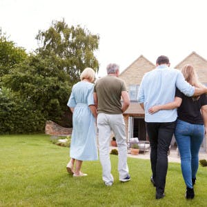 An older couple and younger couple walk together in their yard.
