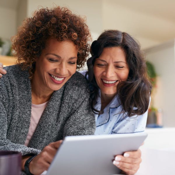 A female couple excitedly looks at homes on their tablet