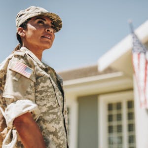 Military woman standing in front of house