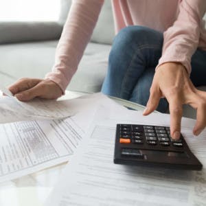 A woman uses a calculator while looking at loan application documents.