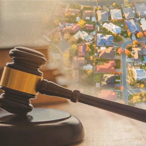 A gavel against a backdrop of an aerial view of suburban homes.