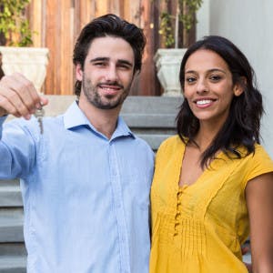 Hispanic/Latino couple holding the keys to their new home