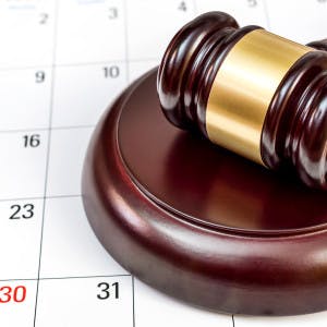 A judge's gavel on top of a calendar page